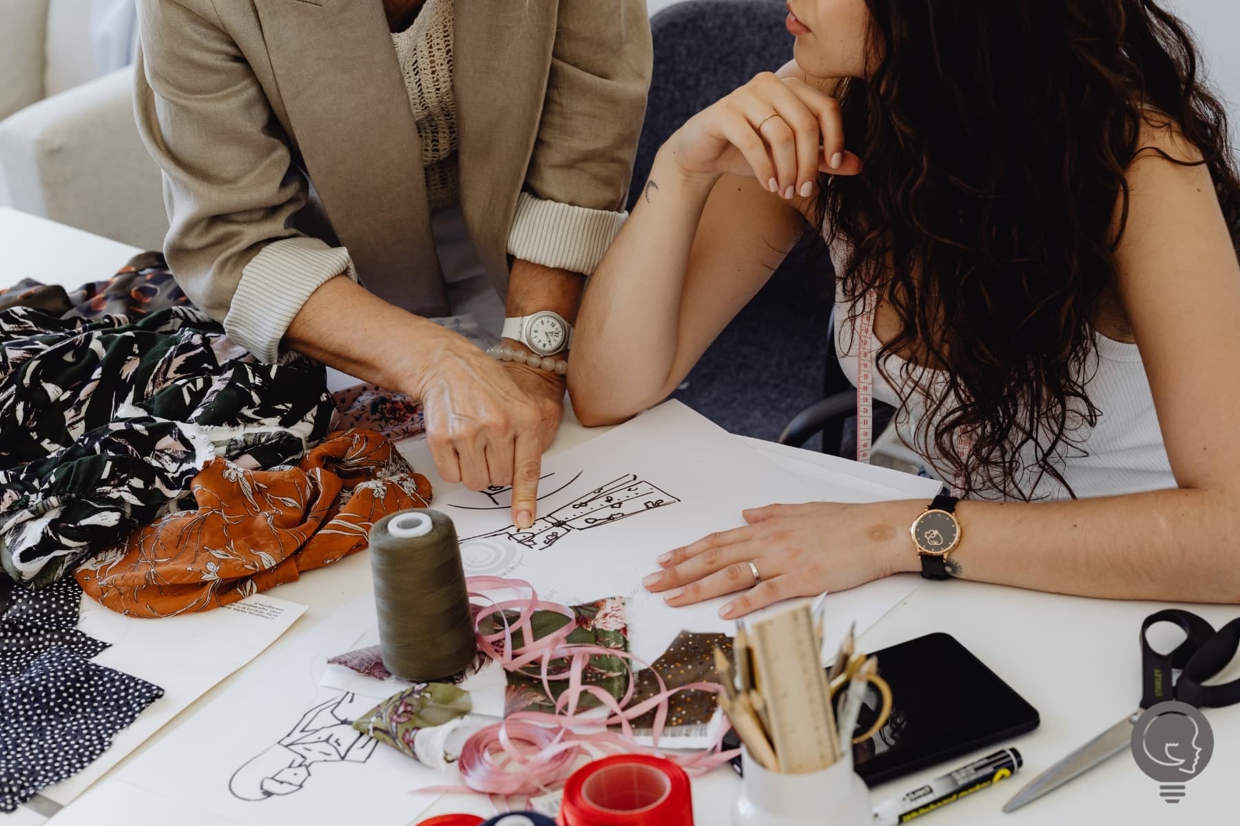 the hands of two women in discussion over fashion design and gross margins